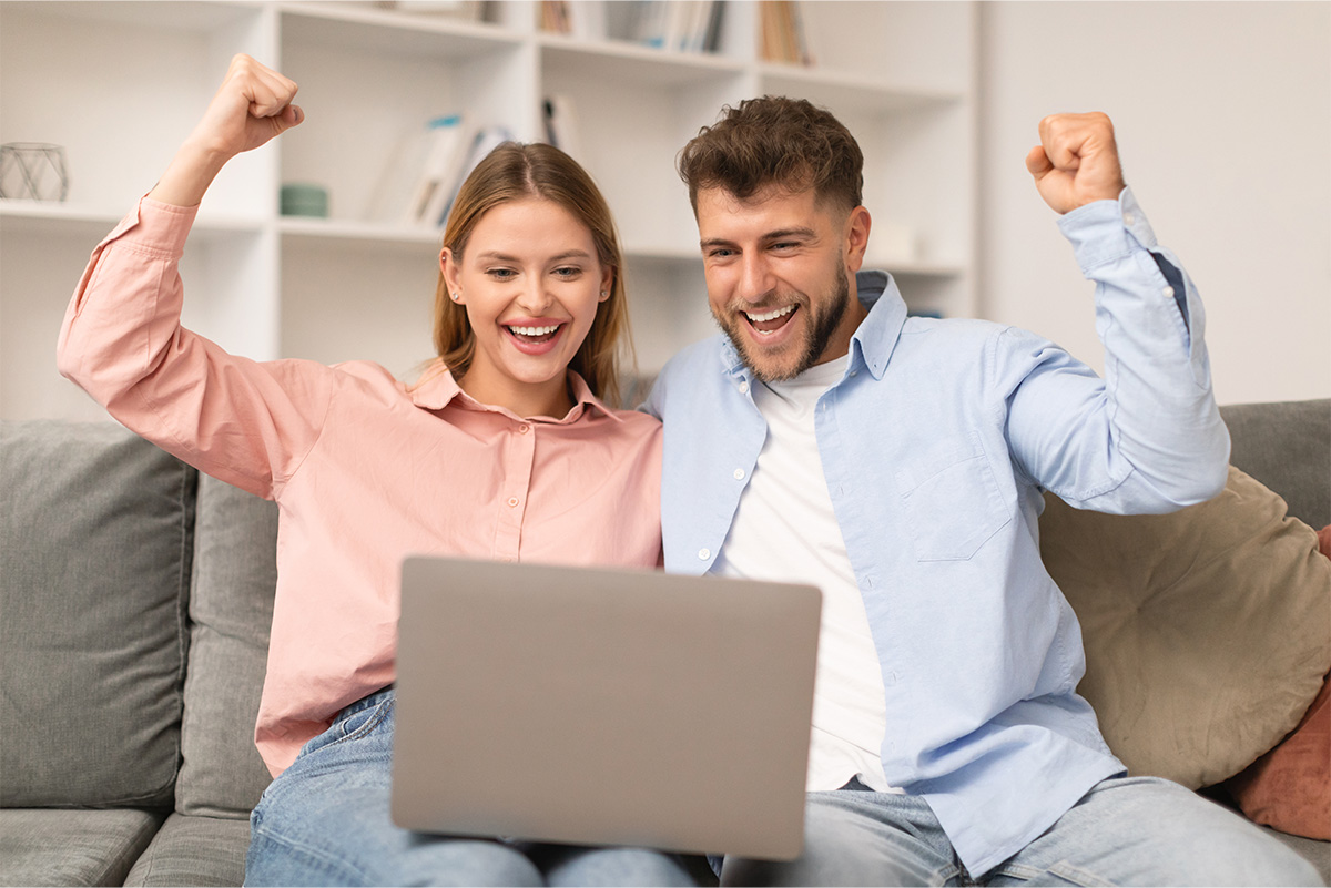 Couple québécois souriant devant un ordinateur après avoir trouvé une option de prêt rapide en ligne.