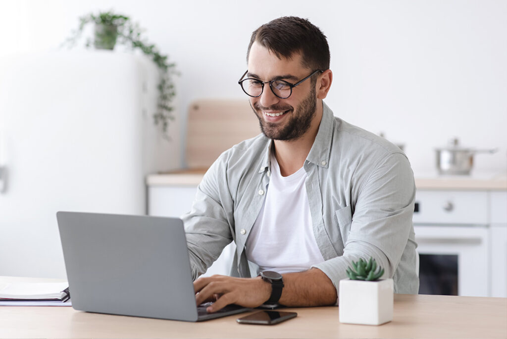 Homme québécois souriant utilisant son ordinateur pour comparer des prêteurs fiables sur AlterCrédit.