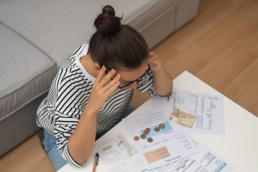 Femme stressée devant ses factures et ses paiements, illustrant un besoin urgent d’un micro-prêt de 1 500 $.
