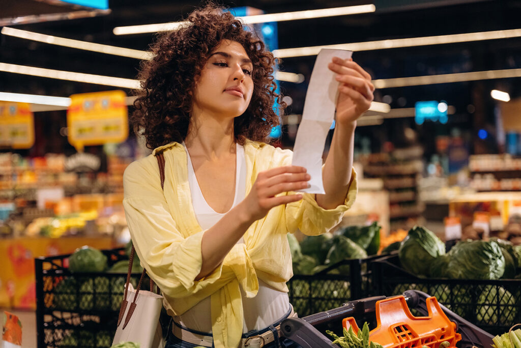Femme examinant son reçu d’épicerie pour gérer une petite dépense imprévue.