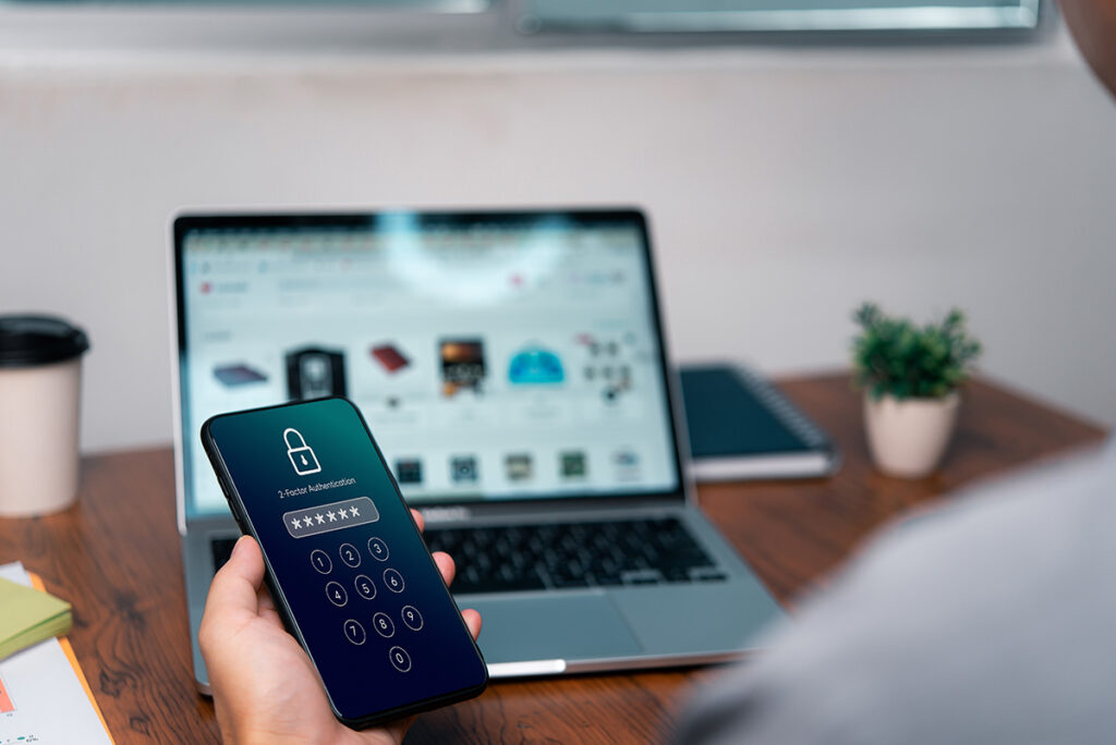 Écran de téléphone affichant une authentification sécurisée à deux facteurs devant un ordinateur, illustrant la sécurité de l’IBV.